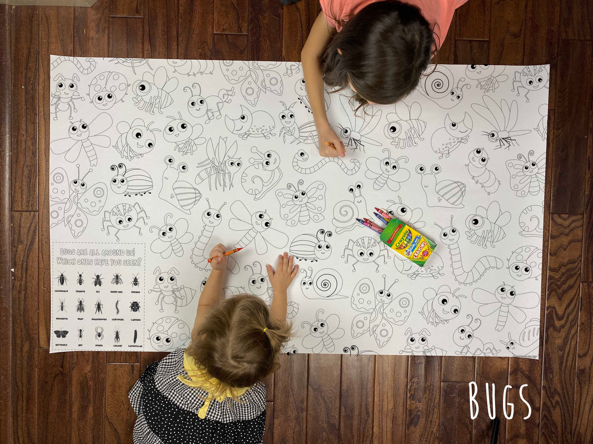 Child coloring the Bugs giant coloring sheet on a wood floor with crayons