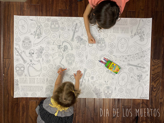 Child coloring the Dia De Los Muertos giant coloring sheet on a wood floor with crayons