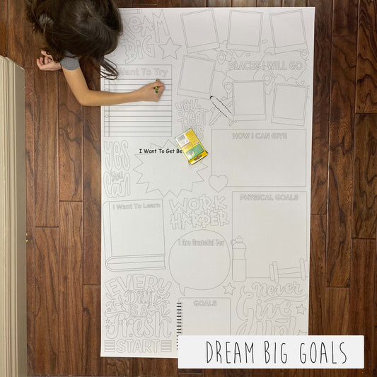 Child coloring the Dream Big Goals giant coloring sheet on a wood floor with crayons