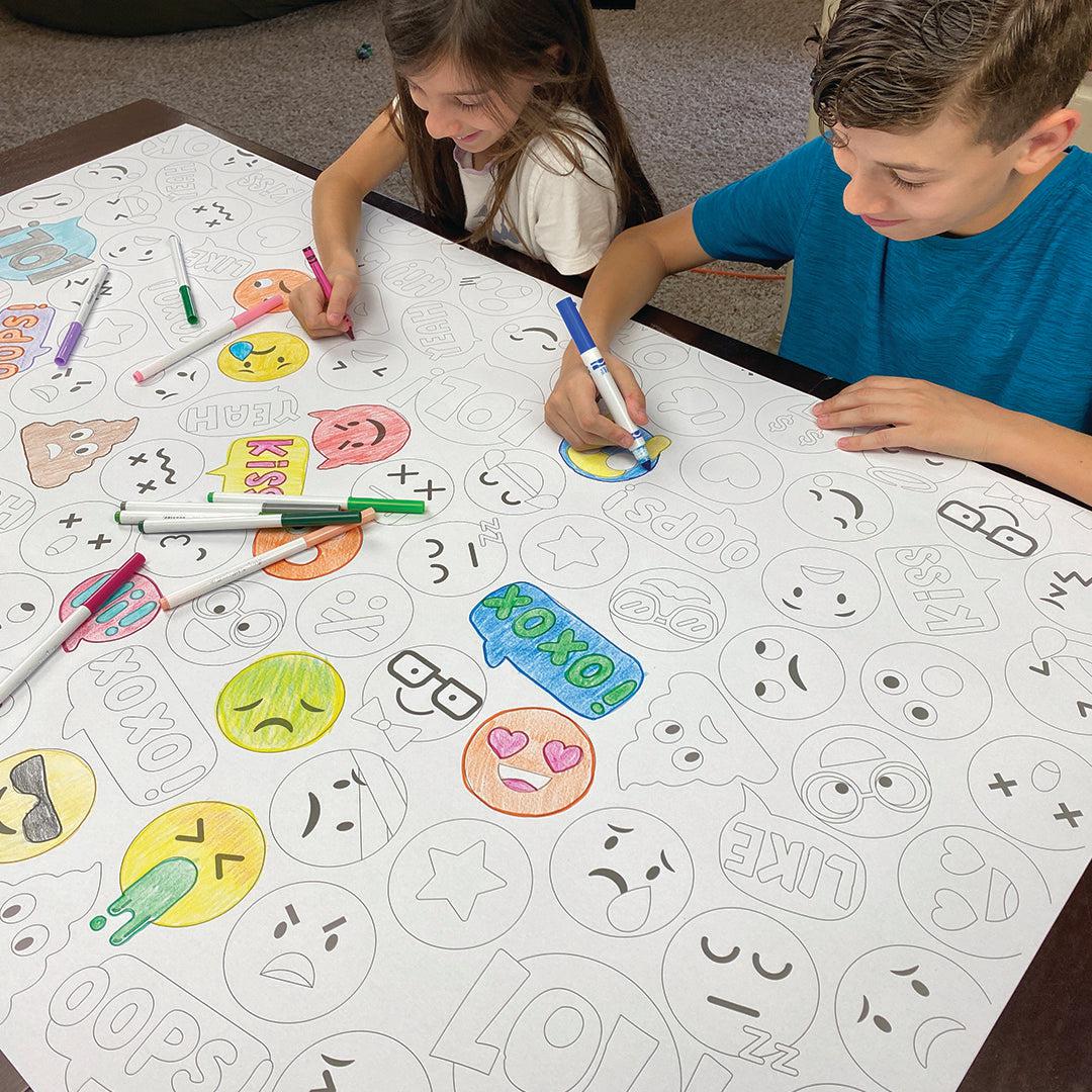 The Emoji giant coloring sheet being colored in with markers at a table