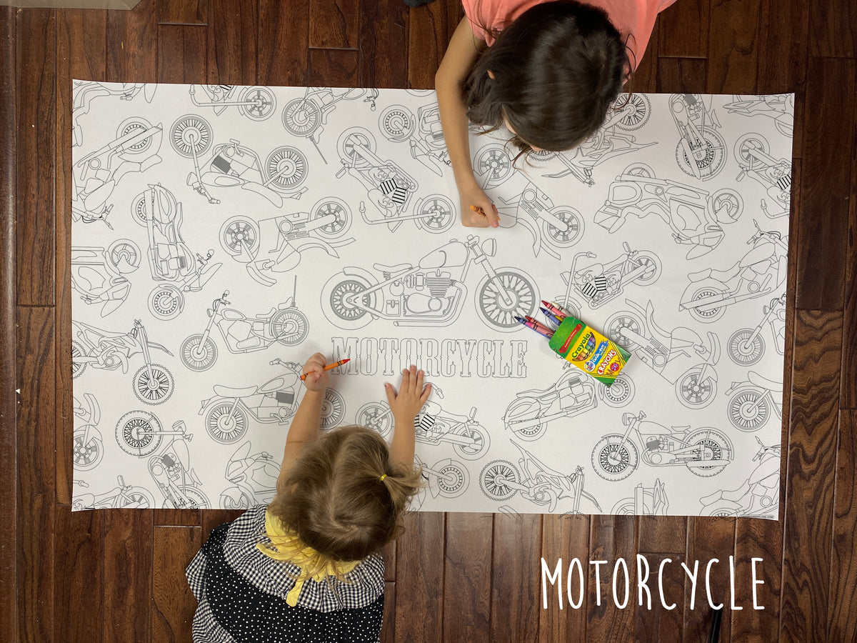 Child coloring the Motorcycle giant coloring sheet on a wood floor with crayons
