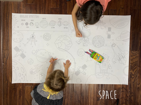 Child coloring the Space giant coloring sheet on a wood floor with crayons
