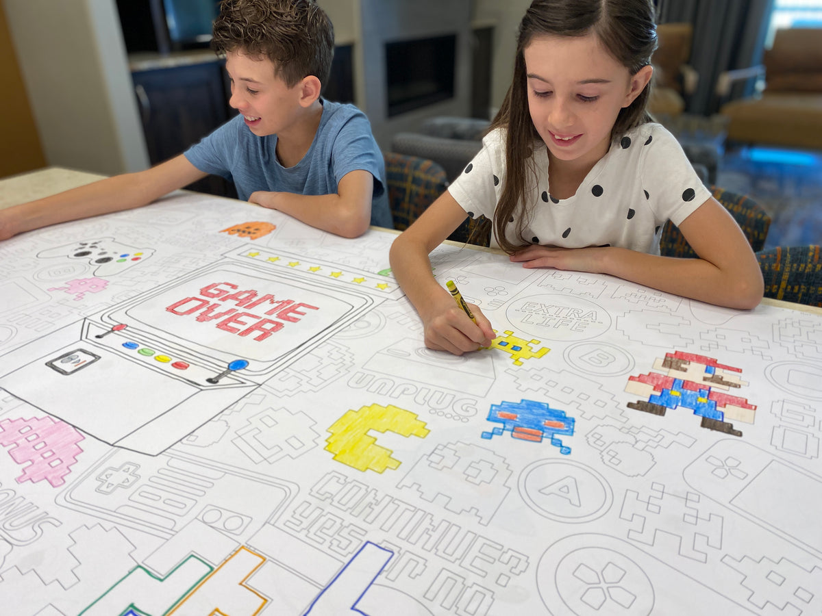 The Video Game giant coloring sheet being colored in with markers at a table